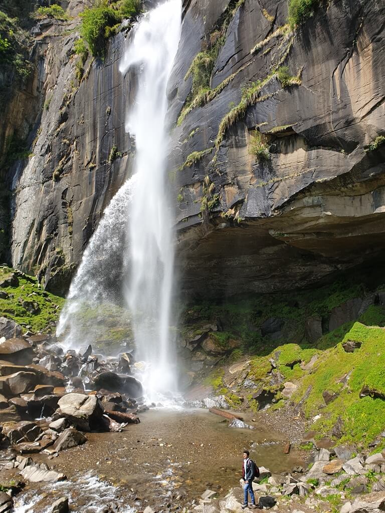 The Jogini waterfall stands tall amidst rocky outcrops, thundering down into a small pool