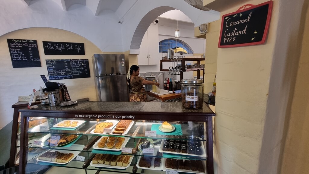 The cafe serves freshly baked cakes, tarts, organic teas and coffees, fresh fruit juices, kombucha, kulfis, samosas, sandwiches, dosas, idlis & ice cream