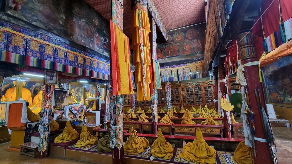 Multiple rows of seats for monks and statues of Buddhist deities inside the Assembly Hall