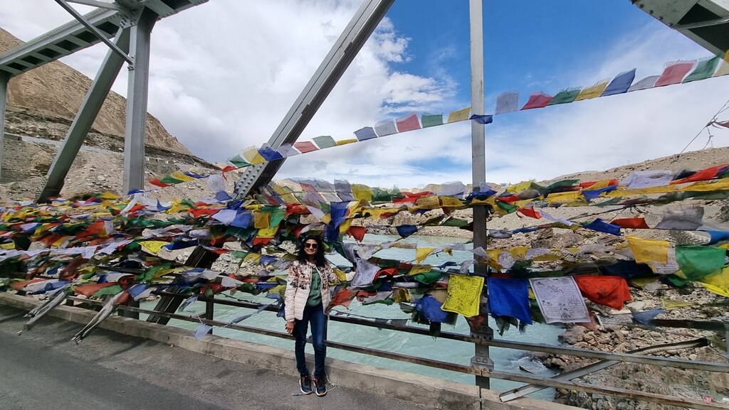 My mum at the colourful steel bridge decorated with Tibetan prayer flags over the Indus river